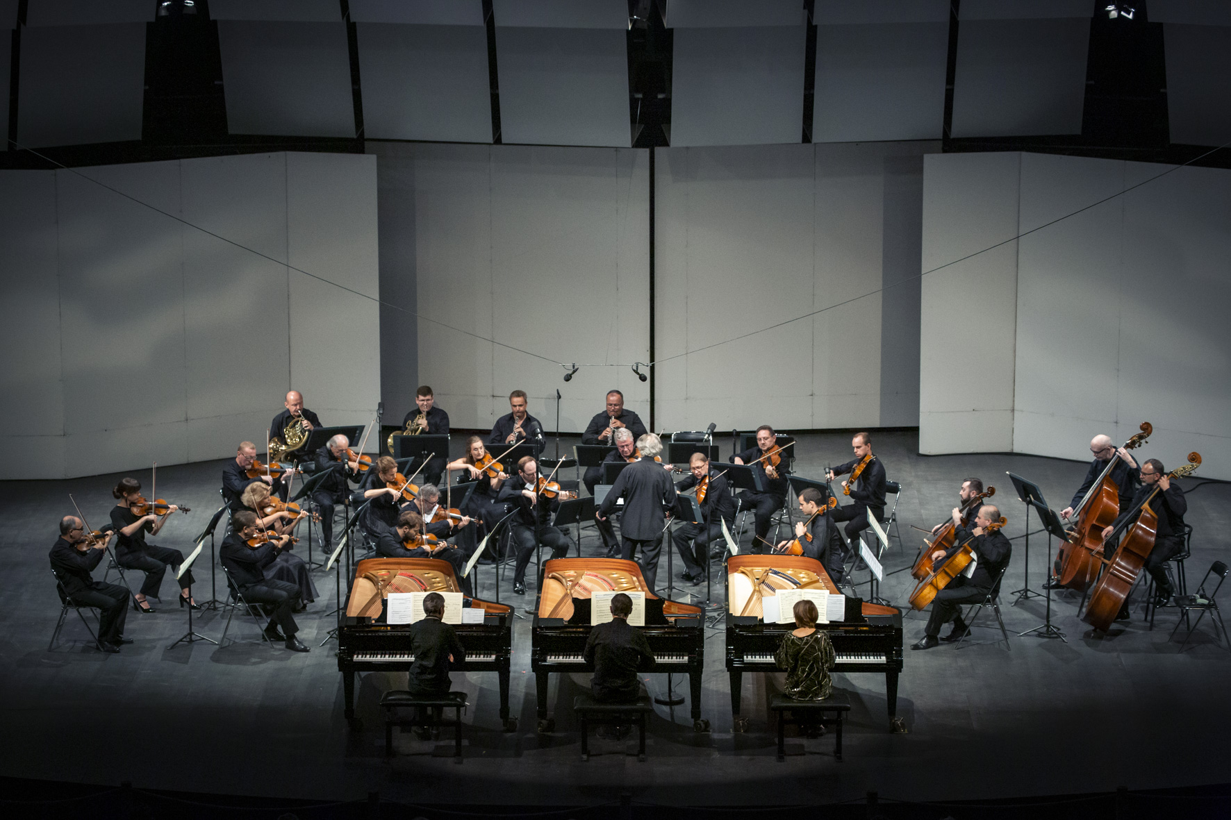 Muzycy orkiestry wraz z solista i dyrygentem grają na scenie w czasie koncertu