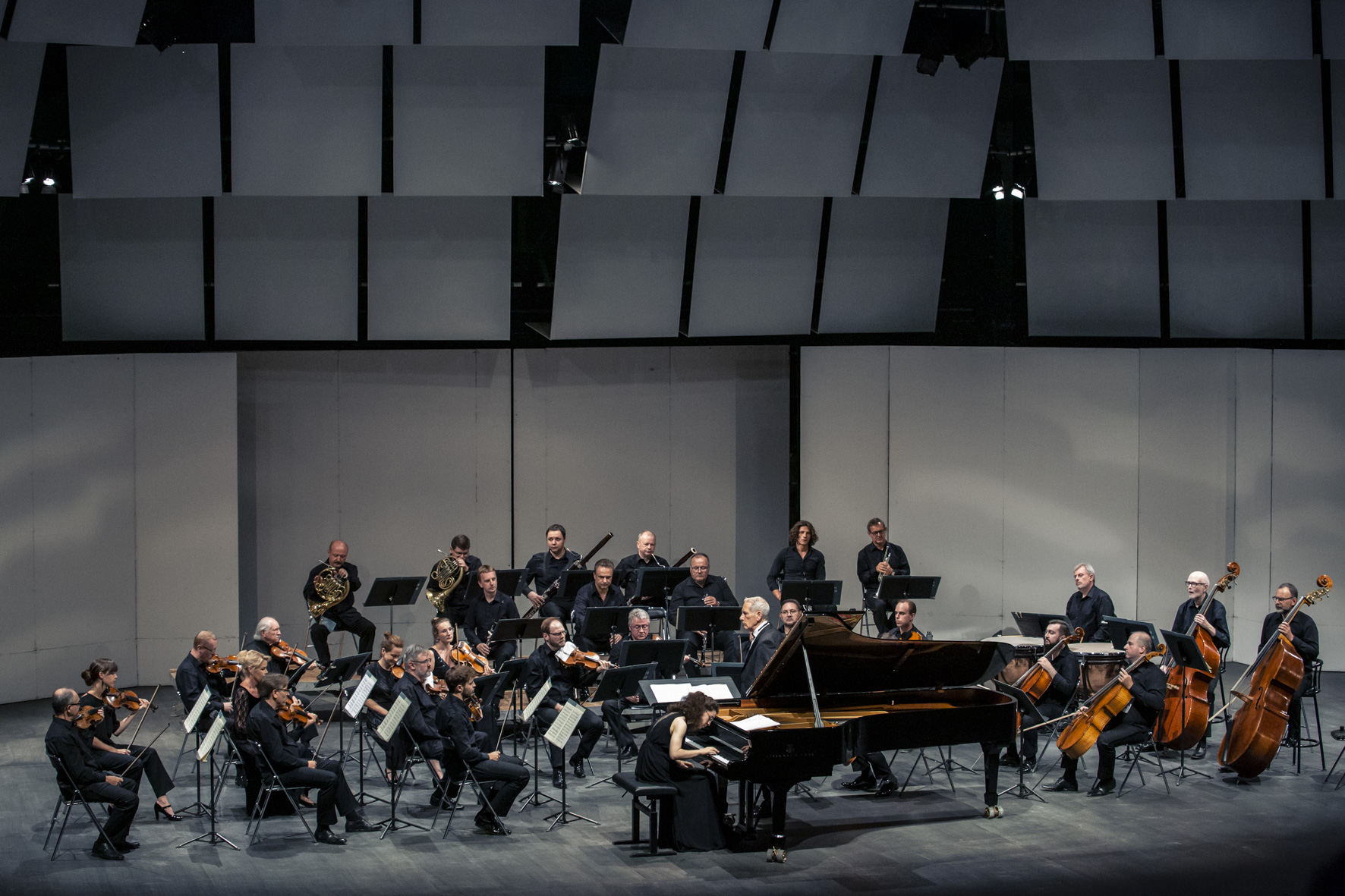 Muzycy orkiestry z dyrygentem i solistą grają w czasie koncertu