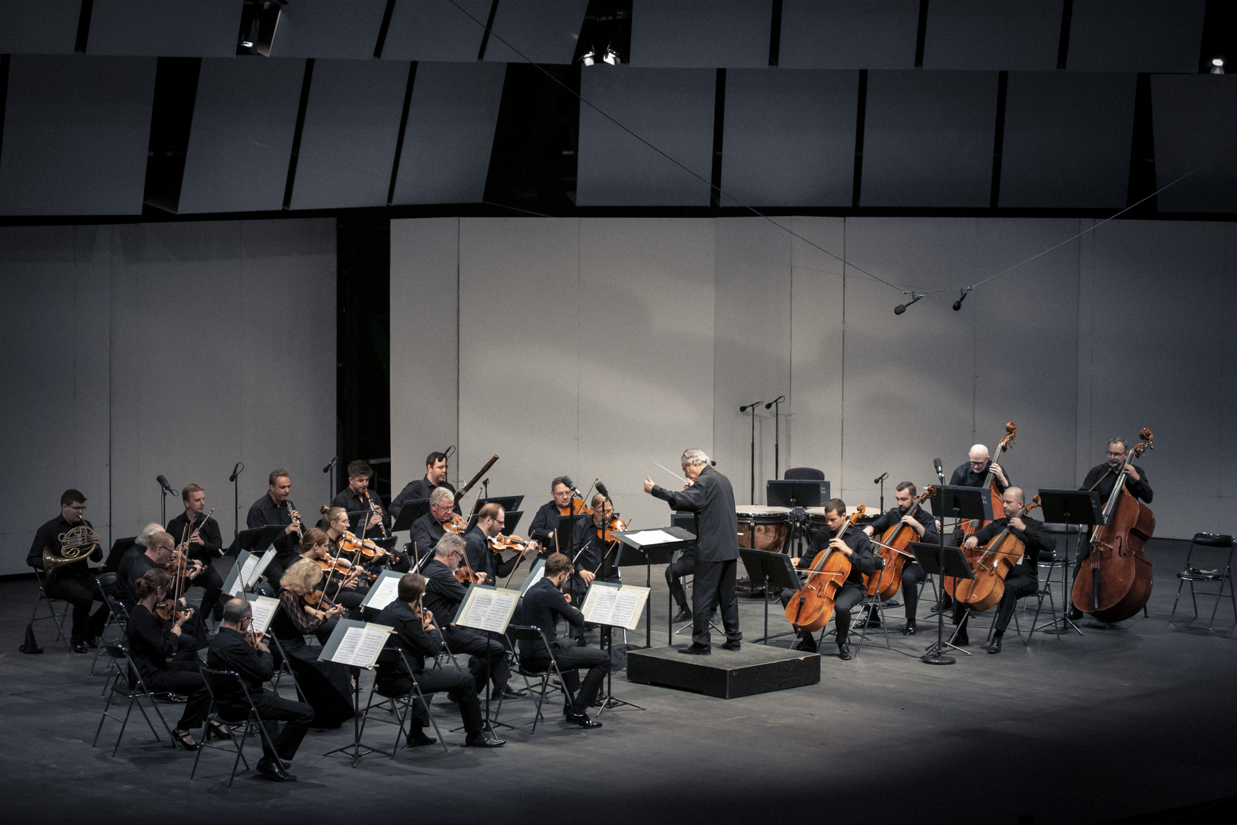 Muzycy orkiestry wraz z solista i dyrygentem grają na scenie w czasie koncertu